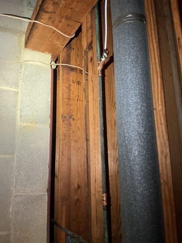 Successfully removed corroded copper ice maker line and outdated saddle valve in basement, replacing them with a proper tee fitting and new shut-off valve. Installed new ice maker supply line to refrigerator, addressing significant pitting and oxidation observed on the original copper piping to prevent further leakage.