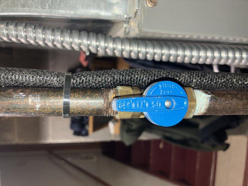 Performed standard MVP heating system maintenance service, inspecting the water supply plumbing components including the copper pipe with blue shut-off valve and insulation. Examined the control circuit board for proper operation, verifying all wire connections (white, yellow, blue, green, pink, and black) were secure and that electronic components showed no signs of damage or failure.