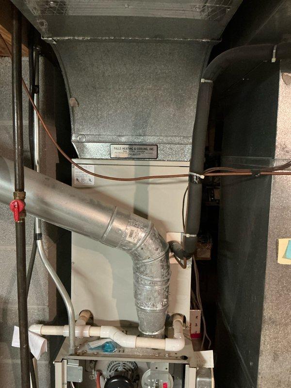 Completed installation of 80% furnace, air conditioning system and hot water tank in utility area. Installation included proper routing of galvanized metal ductwork with appropriate transitions and elbow joints, connection of copper refrigerant lines, and installation of PVC condensate drainage system. All components were professionally mounted and secured to concrete block walls with proper clearances maintained.