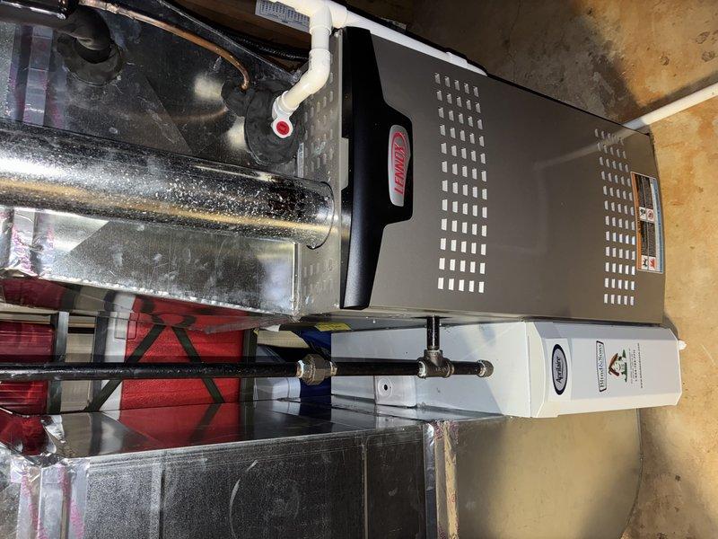 Completed scheduled maintenance service on a 4-year-old Lennox heating system. Inspected all components including furnace, humidifier, ductwork, and PVC condensate drainage system; all systems functioning properly with no issues detected. Documented system condition with photos showing main furnace unit, connected components, and metallic ductwork for service records.