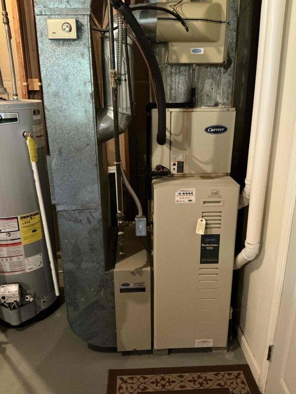 Completed installation of a 90% efficient Carrier Comfort 80 furnace, air conditioning system, and humidifier in residential property. System included proper connection of ductwork, electrical components, and PVC drain piping. Outdoor AC unit was properly positioned and protected with weatherproof cover after installation, with all connections to the home's electrical system completed according to specifications.