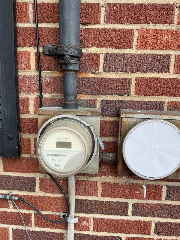 Conducted comprehensive assessment for electrical panel upgrade to 200 amp service and AC replacement. Inspection of existing electrical meter setup on brick exterior wall revealed need for updated service capacity to support new HVAC system. Documented current utility meter configuration and surrounding infrastructure to facilitate proper planning for the upgrade project.