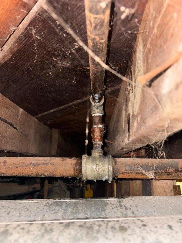 Responded to service call after gas company shut off service due to suspected leak. Inspected gas piping system in crawlspace, observing significant corrosion and oxidation on brass valve and pipe fittings. Identified deteriorated pipe connections with visible mineral buildup and rust as the source of gas leak, particularly at the main coupling junction.