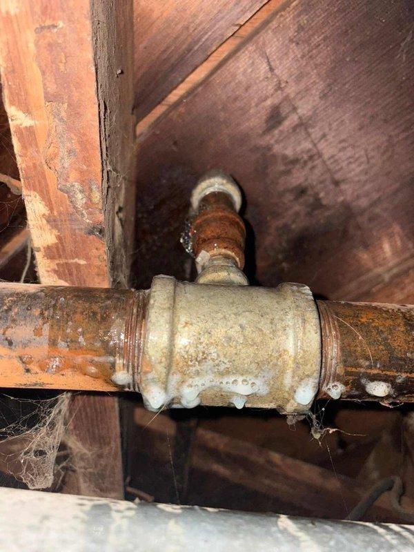 Responded to service call after gas company shut off service due to suspected leak. Inspected gas piping system in crawlspace, observing significant corrosion and oxidation on brass valve and pipe fittings. Identified deteriorated pipe connections with visible mineral buildup and rust as the source of gas leak, particularly at the main coupling junction.