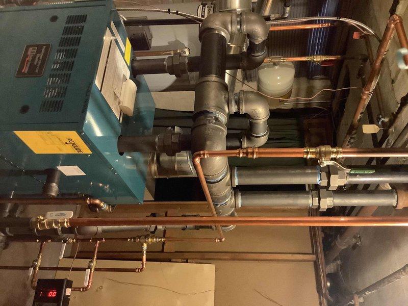 Responded to no heat call and inspected the heating system in basement mechanical room. Performed warranty service on the blue-green boiler unit, checking connections on the extensive copper and PVC piping network. Verified proper operation of pressure gauge, valves, and digital control panel; system is now functioning correctly.
