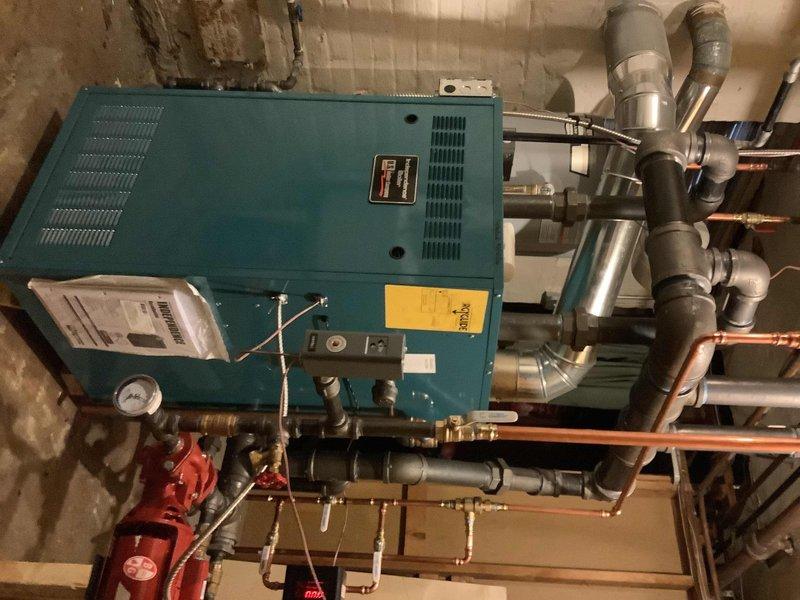 Responded to no heat call and inspected the heating system in basement mechanical room. Performed warranty service on the blue-green boiler unit, checking connections on the extensive copper and PVC piping network. Verified proper operation of pressure gauge, valves, and digital control panel; system is now functioning correctly.