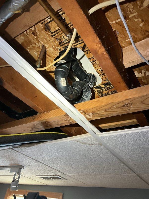 Accessed ceiling cavity to inspect tub drain line requiring replacement. Identified black PVC drainage system with multiple elbows and connections integrated with the existing plumbing infrastructure. Successfully rerouted and replaced the deteriorated tub drain line, ensuring proper alignment with the main waste system.