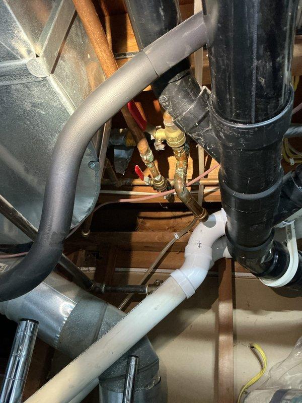 Accessed ceiling cavity to inspect tub drain line requiring replacement. Identified black PVC drainage system with multiple elbows and connections integrated with the existing plumbing infrastructure. Successfully rerouted and replaced the deteriorated tub drain line, ensuring proper alignment with the main waste system.
