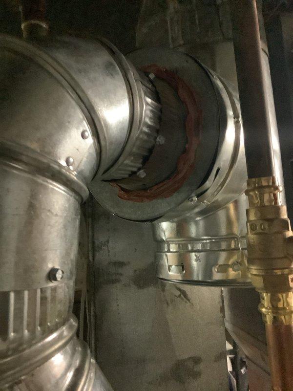 Replaced deteriorated B-vent under warranty in utility area. Installed new galvanized metal ventilation pipe with proper connection joints and fasteners. Inspected and verified all connections are secure with appropriate sealing material at the circular joint elbow section.