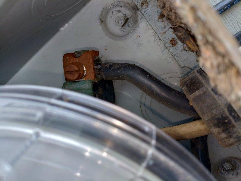 Inspected electrical system due to flickering lights in bathroom and basement, particularly when washer and dryer operated simultaneously. Examination revealed an outdated fuse box with significant corrosion and oxidation damage on terminal connections. Documented extensive rust on mounting brackets and deterioration of connection points that were causing intermittent power supply issues.