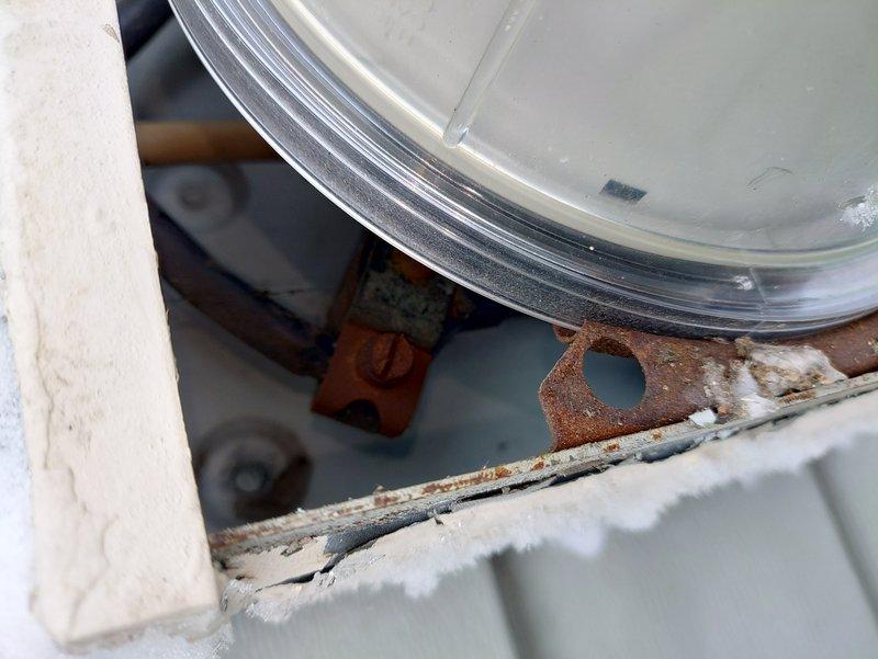 Inspected electrical system due to flickering lights in bathroom and basement, particularly when washer and dryer operated simultaneously. Examination revealed an outdated fuse box with significant corrosion and oxidation damage on terminal connections. Documented extensive rust on mounting brackets and deterioration of connection points that were causing intermittent power supply issues.