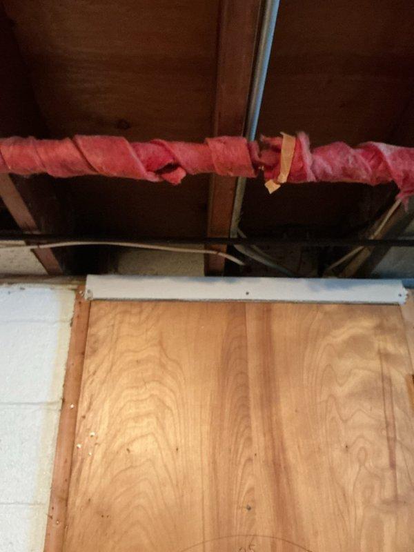 Located and repaired a pinhole leak in corroded copper supply line in basement. Removed deteriorated red insulation to access the affected pipe, which showed significant greenish-blue oxidation. Replaced damaged section of pipe to prevent further water damage to surrounding wooden structural elements.