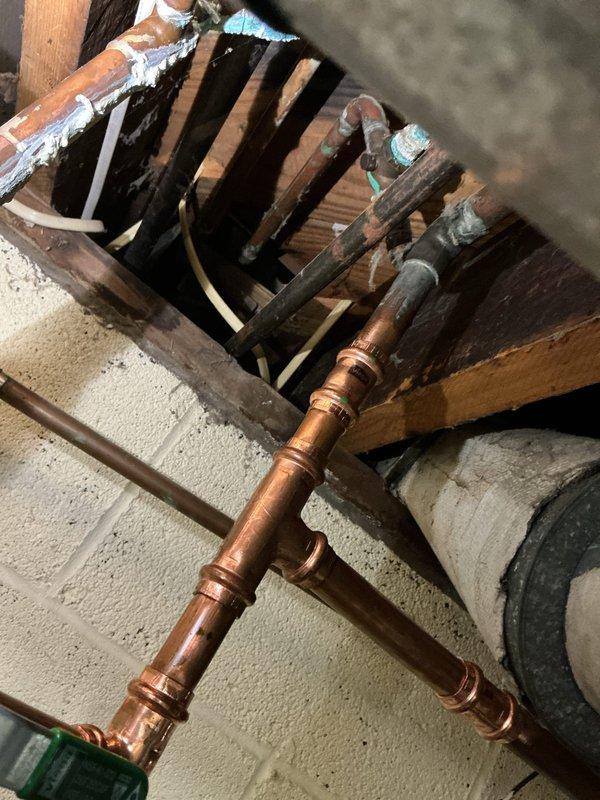Completed quote for water heater replacement in an 80-year-old residence. Inspection revealed aging copper plumbing infrastructure with multiple fittings and joints in the basement utility area. Current system includes copper supply lines, exhaust flue, and shut-off valves that would require updating during replacement to meet current code requirements.