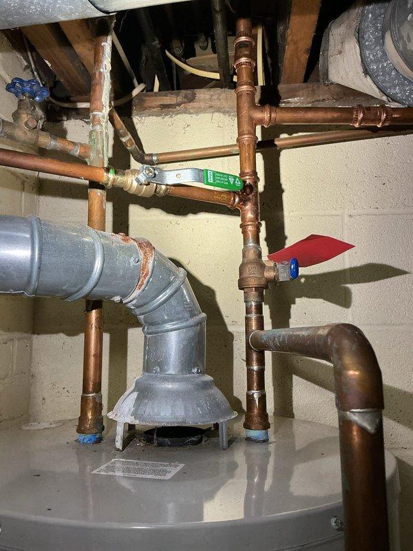 Completed quote for water heater replacement in an 80-year-old residence. Inspection revealed aging copper plumbing infrastructure with multiple fittings and joints in the basement utility area. Current system includes copper supply lines, exhaust flue, and shut-off valves that would require updating during replacement to meet current code requirements.