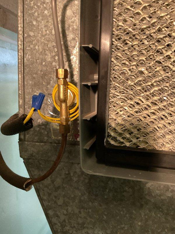 Performed diagnostic assessment on leaking humidifier system. Discovered water intake valve failure causing continuous water flow and subsequent leaking. Inspected access panel and connections to air handler, noting the brass valve fitting and copper supply line required replacement. Replaced defective components and reset control panel to restore proper humidifier operation and prevent further water damage.