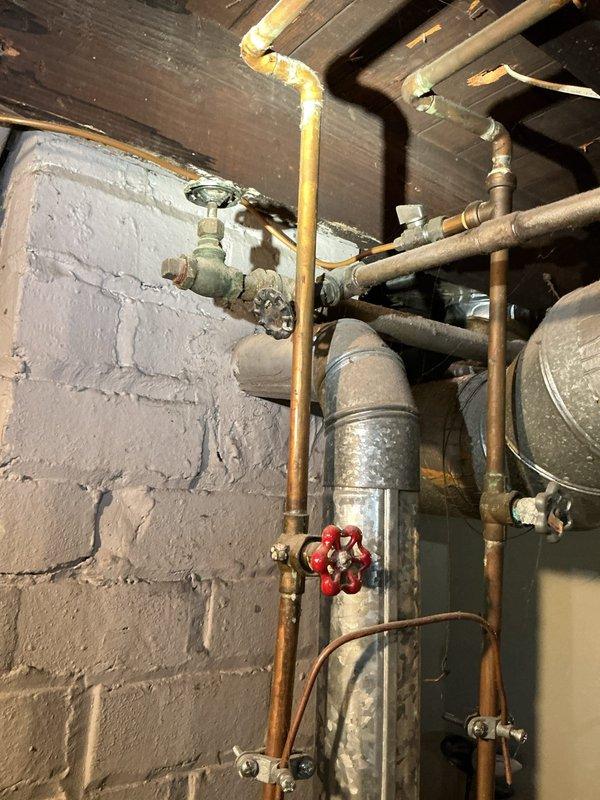 Conducted comprehensive inspection of residential water system to diagnose leaks. Evaluated water softener installation showing two black cylindrical tanks with brine tank, noting deterioration at connection points. Inspected bathtub valve assembly for reported leakage. Documented existing plumbing infrastructure including copper supply lines, galvanized piping, and associated valves for complete assessment and repair recommendation.