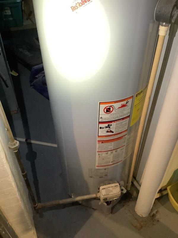 Performed comprehensive inspection of 50-year-old water heater system requiring replacement. Documented existing Kenmore unit with copper pipe connections and metal vent pipe configuration. Evaluated potential Rheem replacement option, noting proper connection requirements for PVC and copper plumbing infrastructure in utility area. Photographs taken of current installation to ensure accurate specifications for replacement proposal.