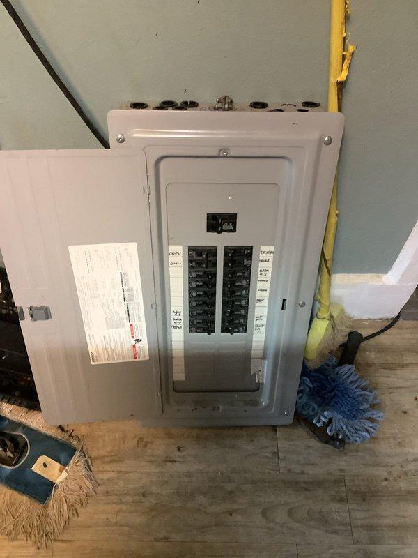 Conducted site assessment for panel upgrade quote at customer's residence. Existing service panel appears to be an older model with standard circuit breaker configuration mounted on a wall in utility area. Noted moisture issues in basement/utility room with visible water damage on concrete block walls, which will need consideration during upgrade planning.