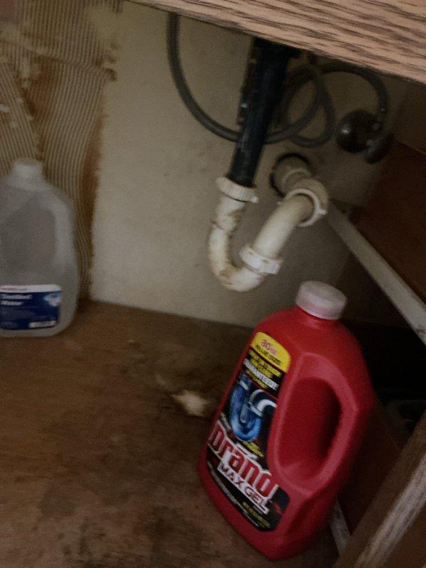 Responded to service call for multiple plumbing issues. Inspected kitchen sink P-trap which showed signs of leakage with visible water damage to cabinet floor and walls. Also examined bathroom toilet with mineral buildup in tank and worn flapper valve causing leakage, and addressed clogged bathroom sink requiring new faucet installation.
