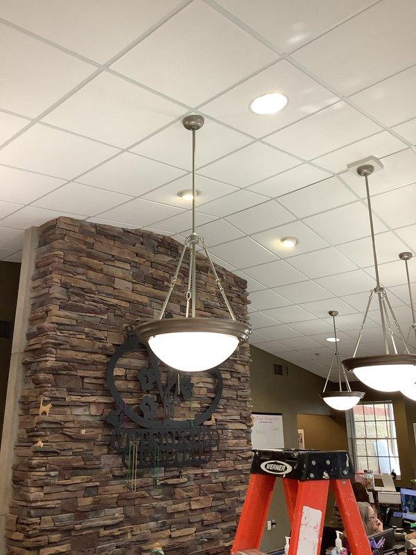 Completed bypass of ballasts on 10 light fixtures and replaced the ballast in the front foyer light fixture. Work involved accessing ceiling-mounted fixtures using ladder in commercial space with drop ceiling tiles and pendant lighting. Parts were received and installation was completed as scheduled.