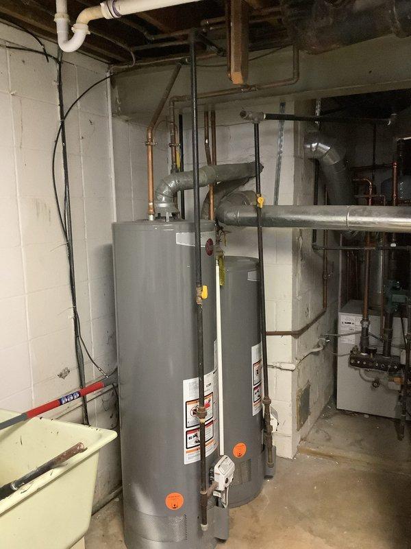 Completed installation of a new mast service with a two-gang meter base and dual 100 amp disconnects on garage exterior, including proper grounding system with new ground rods, waterline ground, and hot water tank bonding. Replaced 100 amp panel in front section of duplex and ran conduit from disconnects to refeed both front and back panels, ensuring complete electrical service upgrade to code requirements.