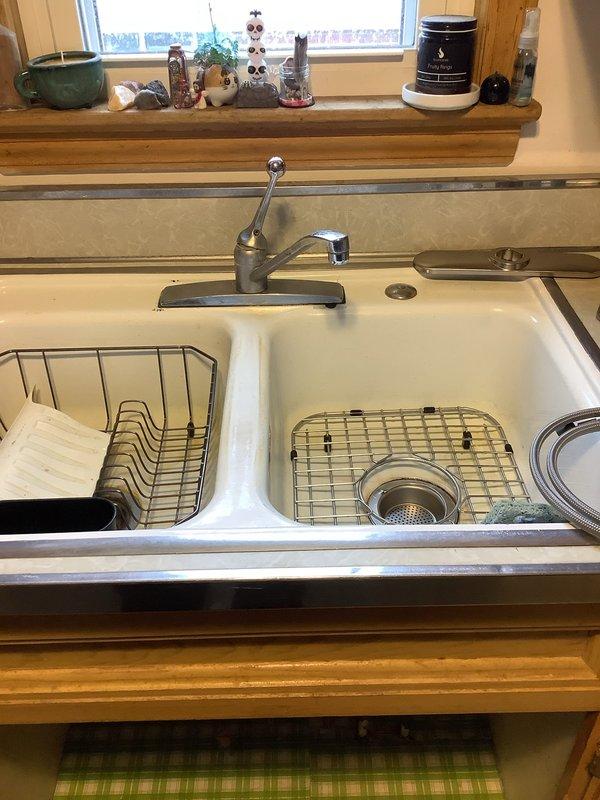 Successfully installed customer-supplied kitchen faucet in double-basin porcelain sink. Completed installation with proper connections and verified functionality. No additional parts were required for the installation.