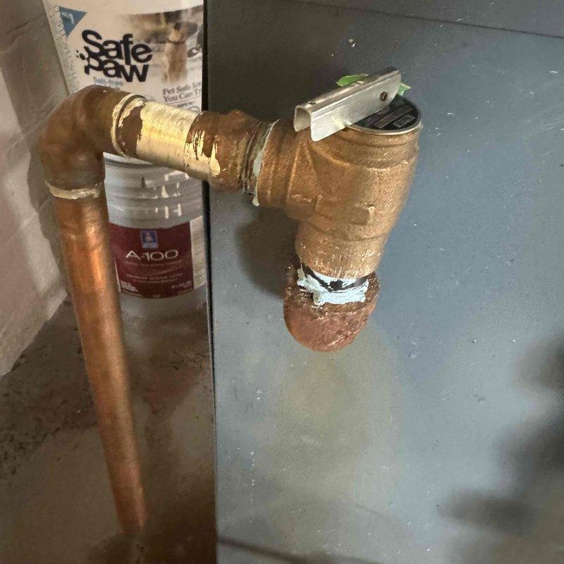 Responded to emergency call for flooded basement caused by boiler pressure safety valve discharge. Upon inspection, found significant corrosion at connection points and valve assembly, particularly at brass fittings showing substantial oxidation. Replaced damaged pressure relief valve to restore proper system operation and prevent further water discharge.