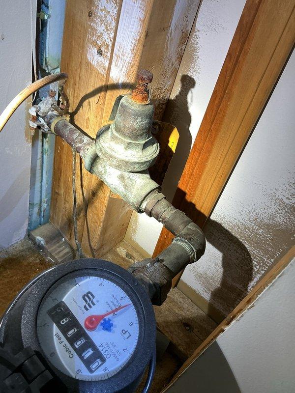 Replaced faulty pressure reducing valve due to excessive water pressure exceeding 100 psi which was causing the temperature and pressure relief valve to leak. Modified plumbing configuration at the meter by installing two isolation ball valves on either side of the new pressure reducing valve, improving accessibility and serviceability of the system.