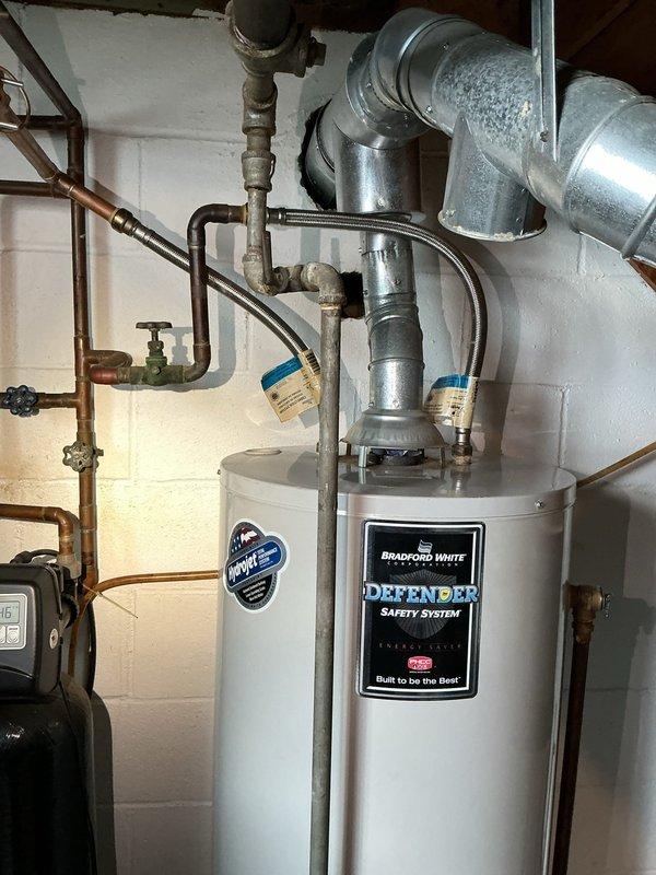 Responded to emergency service call regarding 9-year-old leaking and non-functional hot water tank. Diagnosed significant corrosion and failure on existing unit's connections and tank body. Completed full replacement with new Bradford White Defender Safety System water heater, including installation of new copper supply lines, brass fittings, and proper venting configuration to ensure code compliance and optimal performance.