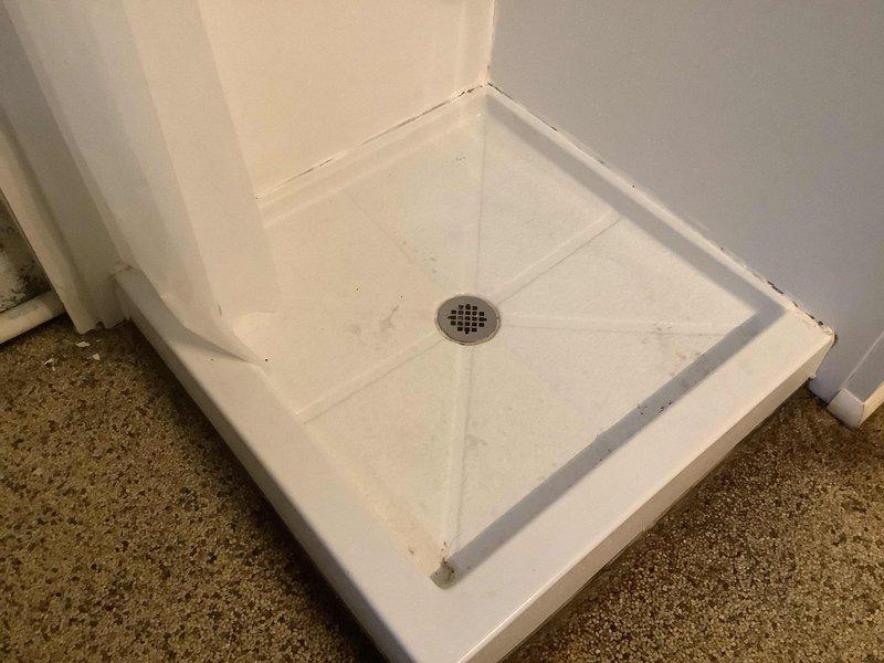 Responded to a water leak service call at a residential property. Inspected bathroom fixtures including toilet with visible moisture damage at the base and a shower pan with staining around edges and drain area. Repaired the leak source and verified proper drainage functionality before completing the service.