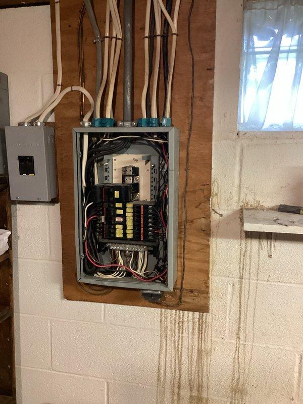 Performed complete replacement of outdated 45-year-old residential electrical panel. Removed existing panel showing signs of water damage and wear as evidenced by staining on surrounding wall. Installed new circuit breaker panel with proper conduit connections and organized wiring configuration to ensure code compliance and improved electrical safety for the home.