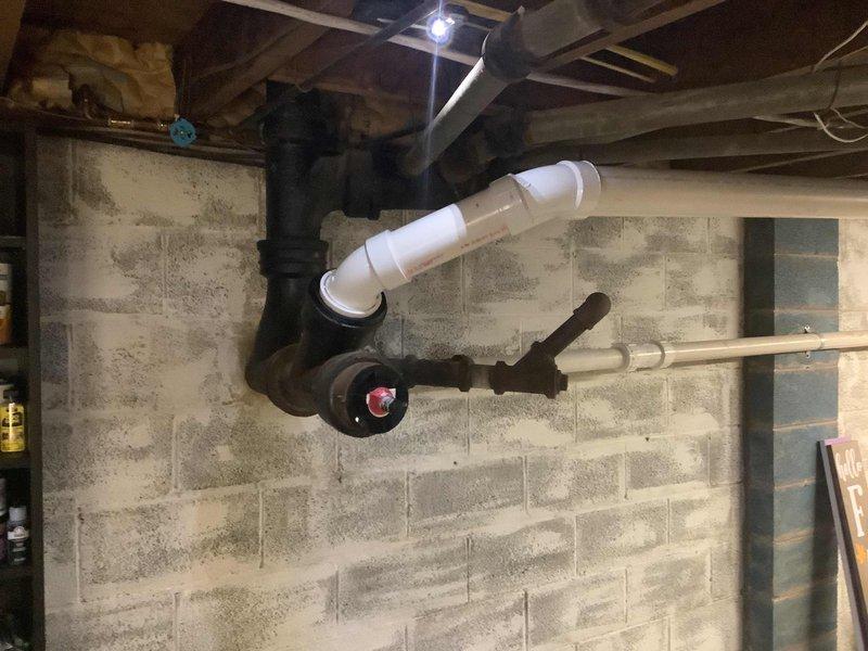 Repaired deteriorated 4" x 3" copper adapter connection at cast iron wye on high rough sewer line using service weight gasket. Modified existing 3" PVC drainage configuration by replacing a long sweep 90° fitting with two 45° elbows to improve flow characteristics and ensure proper drainage.