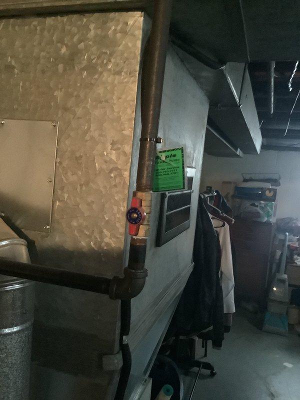 Conducted furnace replacement estimate in basement utility area. Existing unit shows significant age with visible corrosion on connecting copper pipes and plumbing components. Documented current system configuration including ductwork and water connections to provide accurate replacement options.