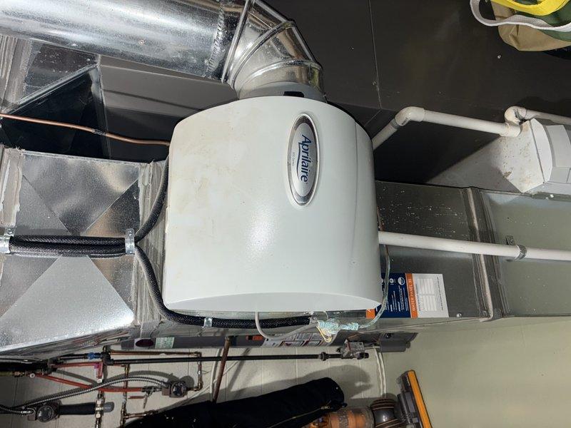 Performed routine maintenance on a 5-year-old gas furnace (BS-MVP Heating Visit). Inspected Aprilaire whole-home humidifier system mounted to ductwork with connected PVC piping. Discovered heavily soiled air filter requiring replacement due to significant dust and contaminant accumulation.