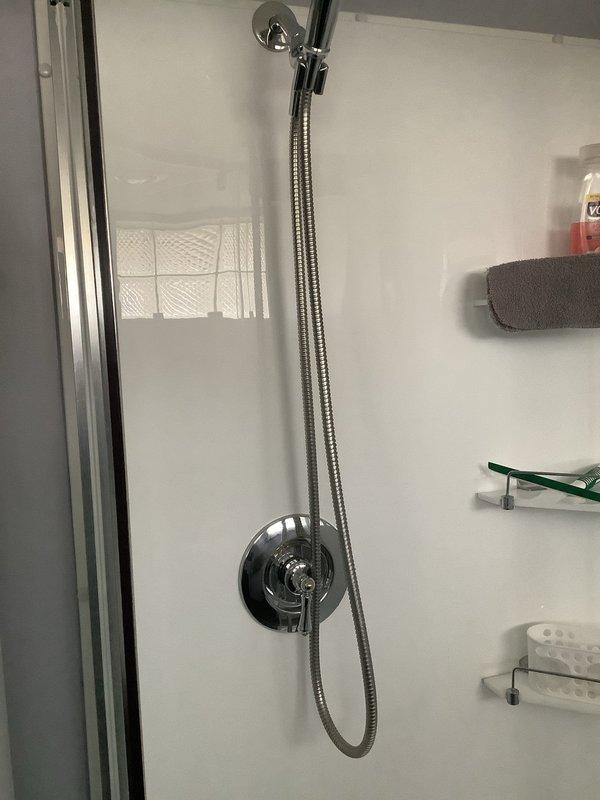 Responded to service call regarding no hot water in shower in 80-year-old home. Upon inspection of the shower fixture and access panel, identified faulty mixing valve causing temperature regulation issues. Replaced mixing valve and tested system, confirming proper hot water flow and temperature control through the handheld shower fixture.