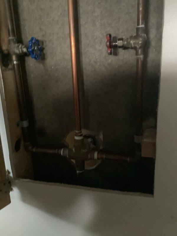Responded to service call regarding no hot water in shower in 80-year-old home. Upon inspection of the shower fixture and access panel, identified faulty mixing valve causing temperature regulation issues. Replaced mixing valve and tested system, confirming proper hot water flow and temperature control through the handheld shower fixture.