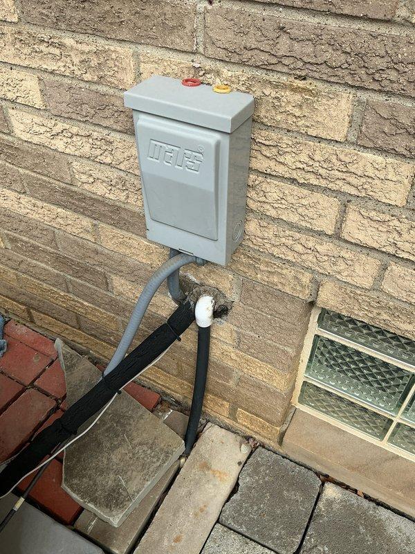 Conducted comprehensive assessment of existing HVAC system requiring replacement. Evaluated outdoor unit mounted on concrete pad with associated electrical disconnect box (MARS brand) and conduit connections. Documented condition of surrounding infrastructure including brick wall mounting surface and adjacent paver patio for proper installation planning.