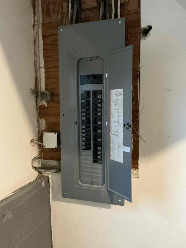 Conducted site assessment for mini-split installation, inspecting electrical panel capacity and identifying optimal indoor unit mounting location in living room (marked with red outline). Verified adequate breaker space for new dedicated circuit and evaluated wall construction for proper mounting support.