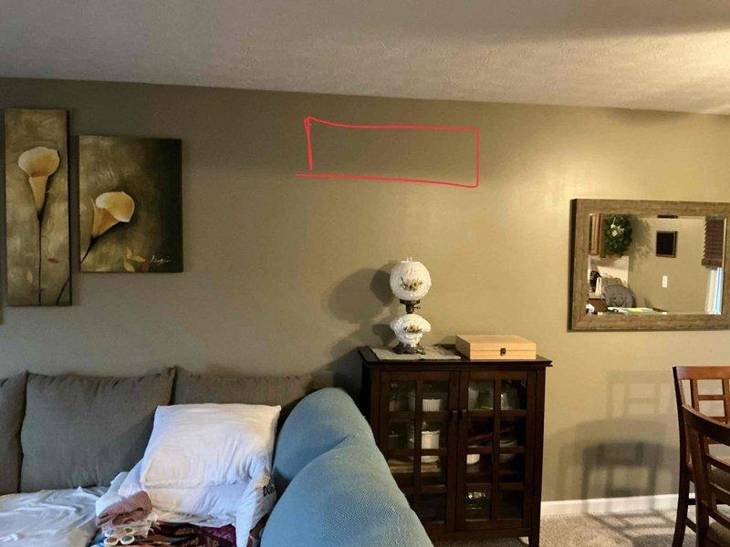 Conducted site assessment for mini-split installation, inspecting electrical panel capacity and identifying optimal indoor unit mounting location in living room (marked with red outline). Verified adequate breaker space for new dedicated circuit and evaluated wall construction for proper mounting support.