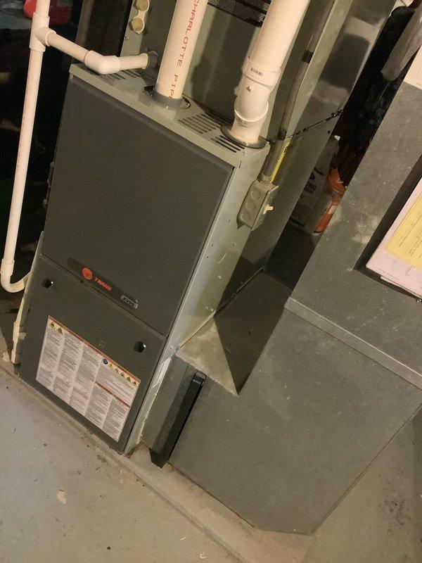 Conducted inspection of 13-year-old furnace and confirmed multiple cracks in heat exchanger with an efficiency rating of 3/5. Documented evidence of deterioration via photographs showing the furnace installation area and the Trane unit with connected PVC ventilation pipes. Recommended replacement due to safety concerns and age of equipment.