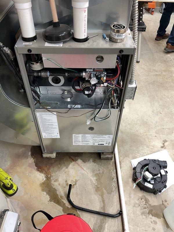 Diagnosed water leakage from newly installed furnace; identified condensate drain pipe issue causing moisture accumulation on concrete floor. Accessed internal components, inspected blower assembly and control boards, then properly secured and realigned condensate drain line to ensure proper drainage and prevent future water leakage.