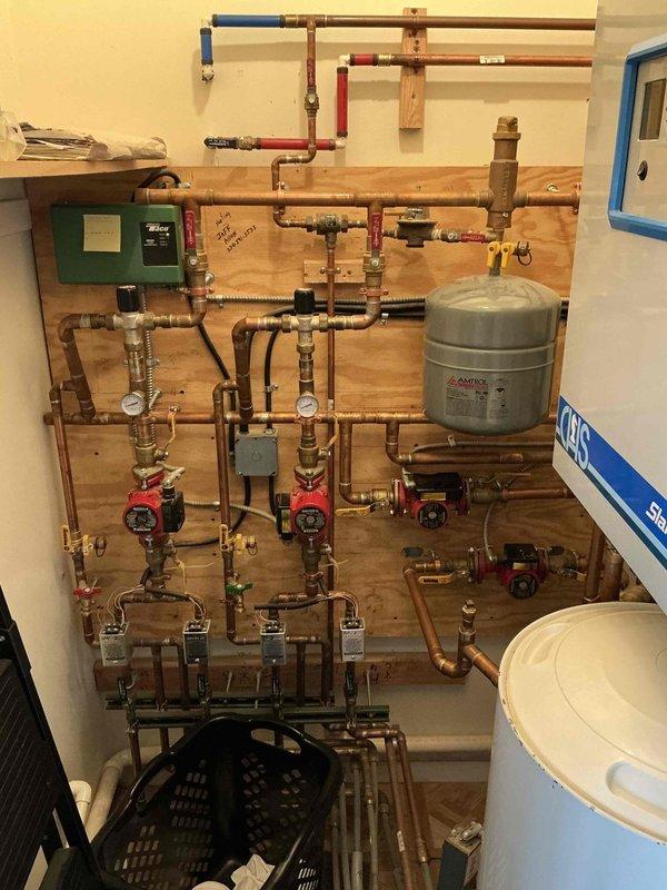 Performed comprehensive assessment of 2013 Navien NCB240-110H boiler system requiring replacement. Inspection revealed complex hydronic heating setup with multiple copper pipe zones, circulator pumps, expansion tanks, and associated valves. Current installation includes a CHS Slant Fin unit with integrated control system. Documented complete system configuration with photos to develop accurate replacement specifications.