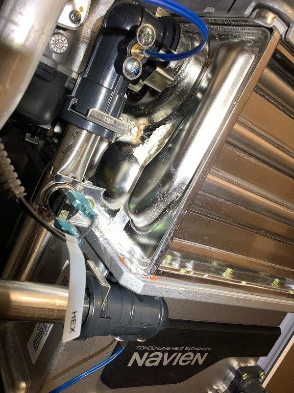 Performed diagnostic inspection on Navien tankless water heater producing insufficient hot water in 23-year-old residence. Examined internal components including condensing heat exchanger, valves, and connection points. Identified mineral buildup and partial blockage in heat exchanger unit affecting performance. Cleaned scale deposits and restored proper water temperature output.