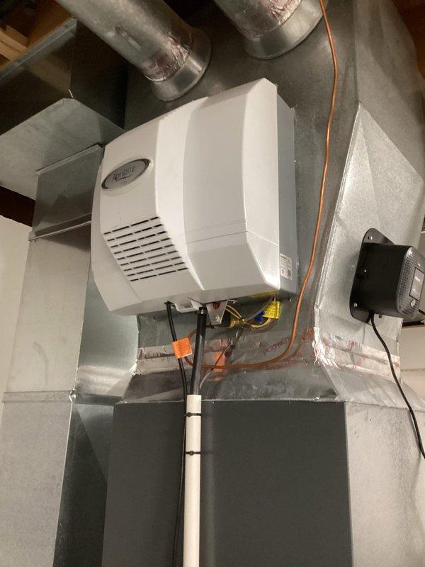 Performed scheduled MVP Heating maintenance service, inspecting the humidifier unit mounted on the HVAC ductwork system and verifying proper connections of water lines and electrical components. Checked the electronic control device (PREMIE) for proper functionality and confirmed all system components are operating normally with no visible damage, leaks, or abnormal wear.