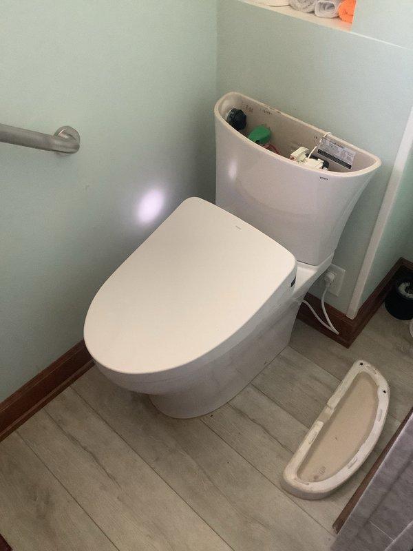 Responded to service call for toilet repair in a 126-year-old home. Upon inspection, found faulty flush mechanism in TOTO toilet with visible mineral deposits at waterline. Replaced green float valve and repaired electrical components of flushing system, restoring proper function to the bidet toilet.