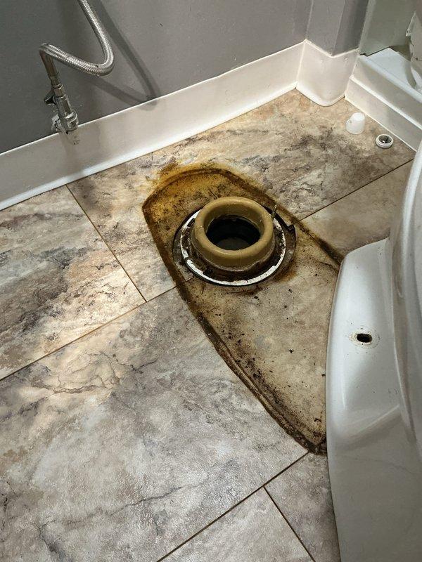 Diagnosed and repaired a leaking toilet in a 65-year-old home, replacing worn internal tank components. Observed significant water damage and staining around the floor drain, indicating long-term leakage that had caused deterioration of the surrounding tile area. Completed full flush test after repair to verify proper operation and no further leakage.