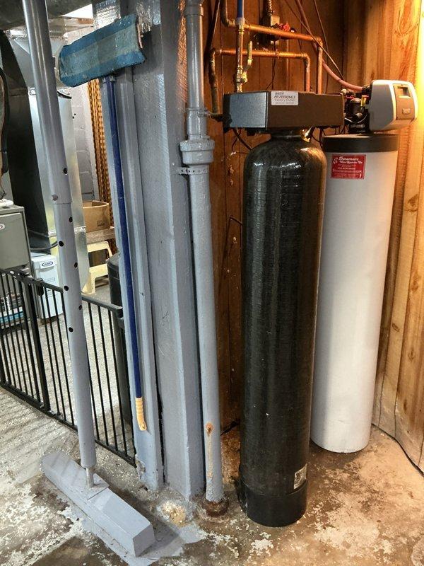 Conducted free estimate for replacement of cast iron vent pipes serving toilet. Inspection revealed visible rust at pipe joints and evidence of moisture damage at wall connections. Documented existing water treatment system including carbon filter tank and water softener with copper supply lines for comprehensive assessment of the plumbing system configuration.