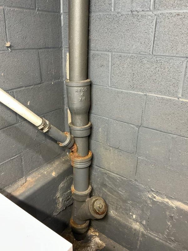 Conducted free estimate for replacement of cast iron vent pipes serving toilet. Inspection revealed visible rust at pipe joints and evidence of moisture damage at wall connections. Documented existing water treatment system including carbon filter tank and water softener with copper supply lines for comprehensive assessment of the plumbing system configuration.