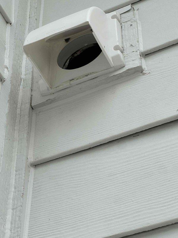 Completed dryer vent cleaning service, removing significant lint accumulation from the exterior-mounted vent on white siding. Observed considerable buildup despite relatively short occupancy period of one year, suggesting potential ventilation efficiency issues. Documented current installation and recommended relocation options for the dryer vent to improve airflow and reduce future lint accumulation.