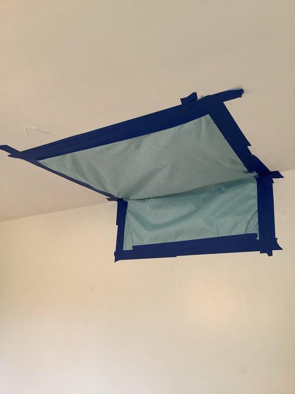 Responded to service call for water leak in upstairs bedroom causing wall cracking. Upon inspection, identified water damage on ceiling with yellowish discoloration and installed protective tarp secured with painter's tape to prevent further interior damage while awaiting comprehensive repair.